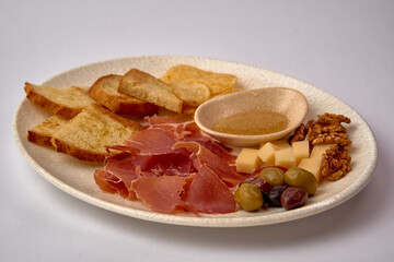 A Beautifully Arranged Platter Featuring Sliced Ham, Cheese, Nuts, Olives, Dried Fruits, and Crispy Bread for Gourmet Experience