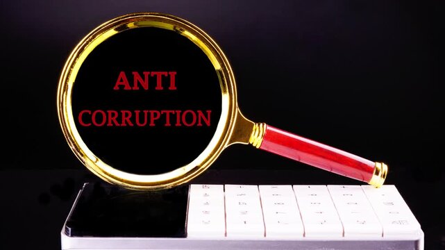 ANTI CORRUPTION text animation in a magnifying glass on a calculator, on a black background. Anti money laundering business and government concept