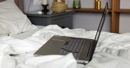 Laptop placed on bed in modern apartment room highlights concept of freelance. Flexible schedule...