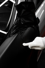 Car detailing applies vinyl wrap around trim using plastic wedge tool for seamless finish. Trim...