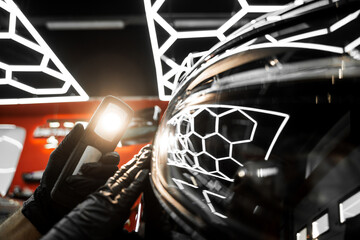 Swirl finder light to detect paint issues on black car in a detailing studio. Car Paint Inspection....