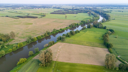 Aerial view of a serene countryside landscape featuring a winding river, lush green fields, and...