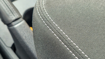 Close-up view of a textured black car seat fabric showing fine stitching details. This image highlights the quality of automotive upholstery and design features.