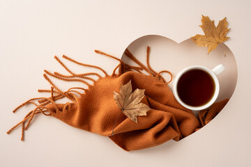 Warm autumn aesthetic with a blanket, tea, and autumn leaves arranged in a heart