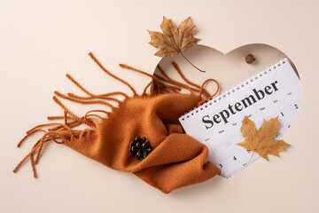 Arrangement featuring a September calendar, orange scarf, and autumn leaves, evoking cozy fall