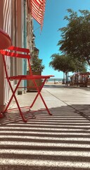 Naklejka premium Red chair, seaside cafe, sunny day, beach view, summer