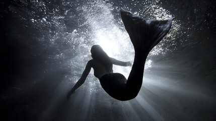 Enigmatic mermaid gracefully swims underwater, surrounded by shimmering light rays filtering through the surface, creating a magical and ethereal atmosphere in the depths of the ocean