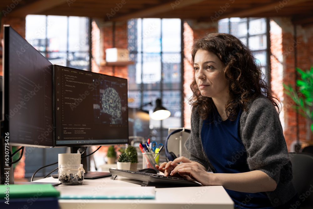 Poster female it engineer doing maintenance on artificial intelligence systems, sitting at office desk. you