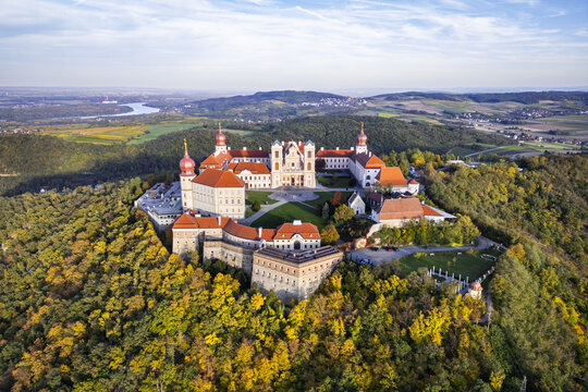 Aerial view of G&Atilde;&para;ttweig Abbey perched atop a hill, its red-roofed buildings contrasting against the surrounding autumn foliage, Krems, Nieder&Atilde;&para;sterreich, Austria.