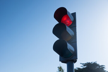 Traffic light showing red signal against clear blue sky