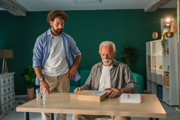 Senior man receiving package from mature son at home