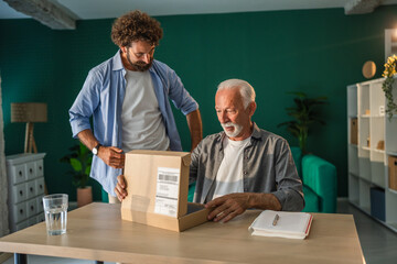 Senior man receiving package from mature son at home