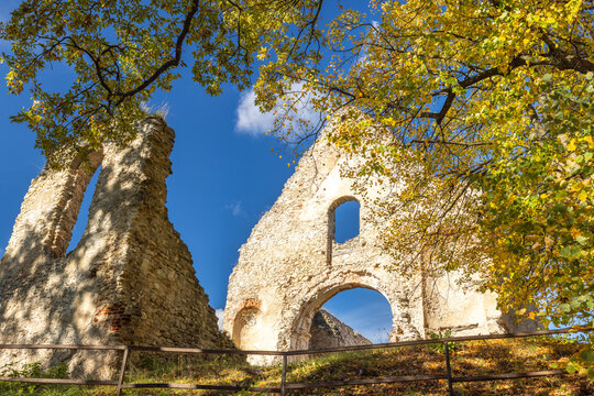 The Katarinka, ruins of a Franciscan monastery and church in Slovakia, Europe. Historic stone ruins against a blue sky, framed by autumnal foliage. Evokes a sense of history and decay.