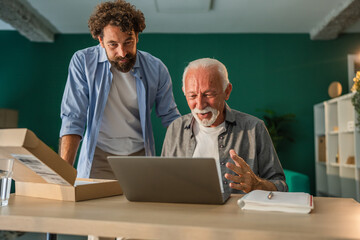 Senior man receiving online shopping assistance from son