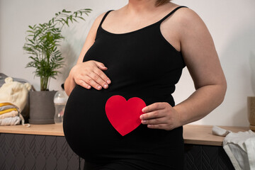 Pregnant woman holding red heart shape and feel love for unborn baby in belly. Awaiting for baby....