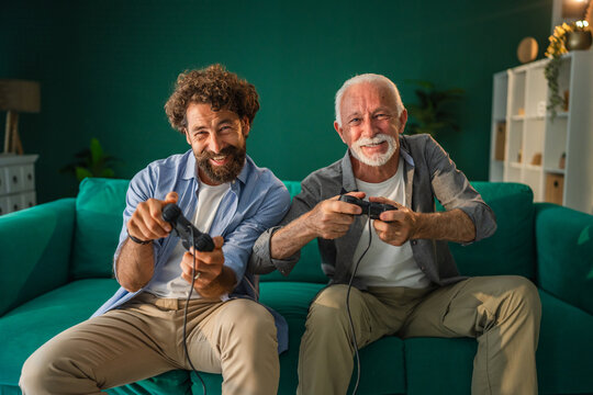Father and son playing video games on sofa at home