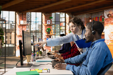 Customer service manager teaching new worker how to track support tickets in dedicated company...