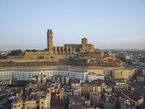Aerial view of the Seu Vella cathedral perched atop a hill, casting a golden hue over the surrounding buildings, Lleida, Lleida, Spain.