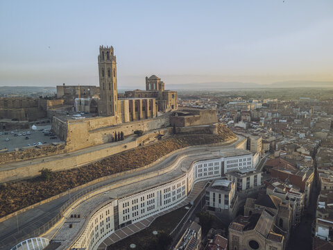 Aerial view of the Seu Vella cathedral and Castell del Rei silhouetted against the dawn sky, overlooking the city's rooftops, Lleida, Lleida, Spain.