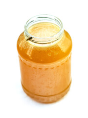 Glass jar of golden bee honey is on a white background. Fine organic product concept. Agriculture and food industry.