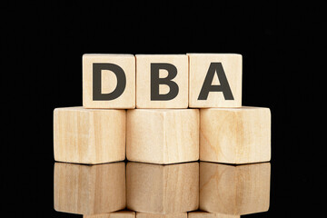 DBA text assembled from wooden cubes on a black background