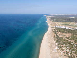 A stunning aerial view of Saros Gulf near Enez, Edirne, Turkey, showing the beautiful turquoise sea, sandy beach, pine forest, and a quiet coastal village under a clear blue summer sky.

