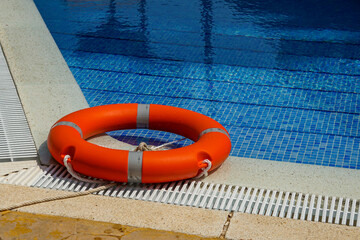Bright Orange Lifebuoy Floating in Blue Pool Water