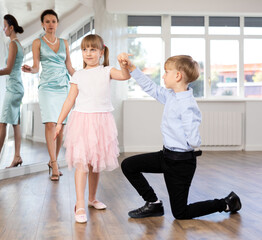 Preteen dancers rehearsing ballroom dance as couple under guidance of female coach in choreography...