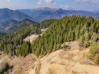 Aerial view of a path winding through a dense forest contrasting with barren patches on a hillside, Å pania Dolina, BanskÃ¡ Bystrica Region, Slovakia.