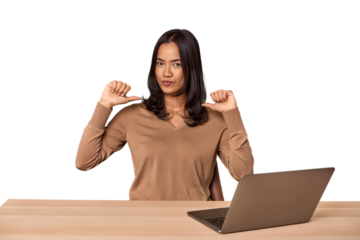 Filipino woman at desk with laptop feels proud and self confident, example to follow.