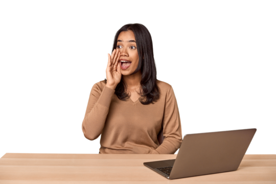 Filipino woman at desk with laptop shouting and holding palm near opened mouth.