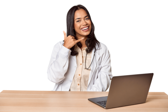 Young Filipino doctor with laptop in studio showing a mobile phone call gesture with fingers.