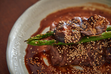 A gourmet dish featuring succulent steak topped with tender asparagus and rich sauce, garnished...