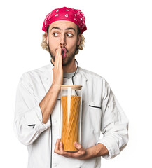 Young chef holds pasta sauce jar in studio is saying a secret hot braking news and looking aside