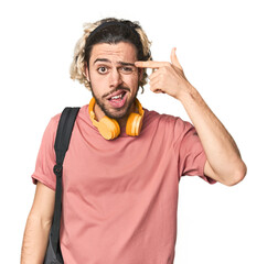 Young student with backpack and headphones showing a disappointment gesture with forefinger.