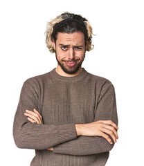 Young Caucasian man in studio setting unhappy looking in camera with sarcastic expression.