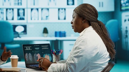 Black general practitioner and patient discussing health care diagnostics and therapy options in a clinic, emphasizing communication and medical expertise. Female expert gives advice. Camera A.