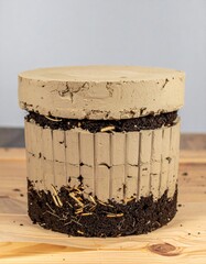 Fototapeta premium Terracotta Pot with Soil and Roots on Wood Table against Gray Backdrop in Studio