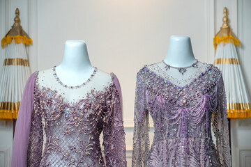 Close-up of two luxurious purple bridal gowns with intricate beading, sequins, and embroidery on...