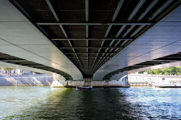 Symmetrical view from beneath urban bridge across Seine River in Paris with reflections