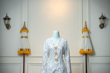 An elegant white bridal gown displayed on a mannequin, featuring intricate lace embroidery and...
