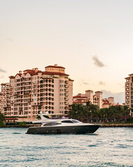 Summer vacation. Fisher island residential building and luxury yacht boat. Boat passing Fisher island, Miami. Motor boat yacht floating to marina. Luxury yacht boat at Fisher island. Romantic trip