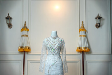 An elegant white wedding dress with long sleeves, adorned with floral embroidery and colorful...