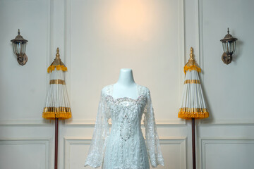 Elegant white bridal gown with lace details and crystal embellishments on a mannequin, displayed...