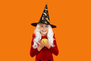 Halloween witch girl isolated on orange. Pumpkin on Halloween. Witch All Hallows costume of girl. October 31 pumpkin. Costume party. Halloween pumpkin in hand of witch girl. Orange gourd