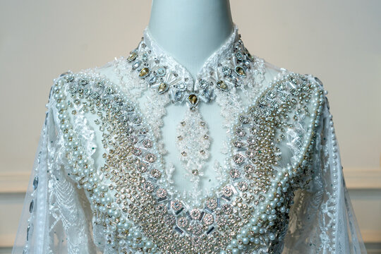Detailed view of an elegant white wedding gown with shimmering beads, crystals, and pearls, designed for a traditional akad nikah ceremony.