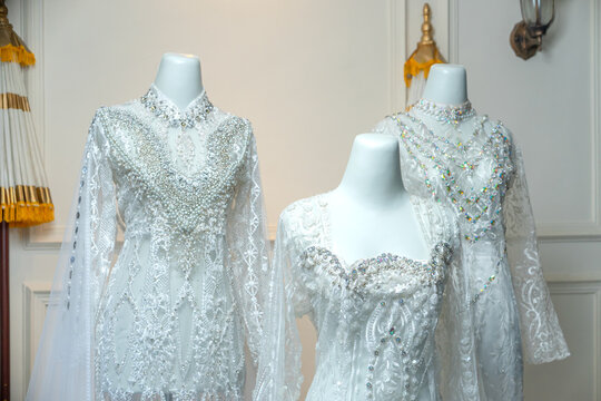 Three intricately designed white bridal gowns are beautifully displayed on mannequins, showcasing rich details of lace, beads, and sequins, ideal for akad nikah and weddings.