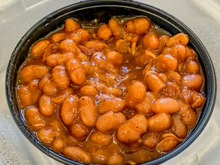 Baked beans in a black plastic ramekin