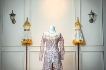 A luxurious long-sleeved pink wedding gown with floral embroidery is elegantly displayed on a...
