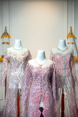 Three luxurious bridal gowns in soft pink hues with detailed embroidery and beadwork, elegantly...